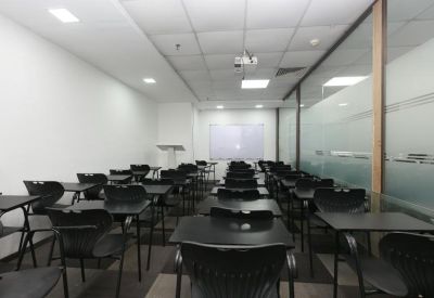 Training room set up with rows of black desks and a projector screen.