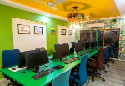 Brightly colored coworking space with green desks and blue chairs.