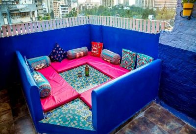 Rooftop terrace featuring vibrant blue walls and a pink floor-seating area with city views.