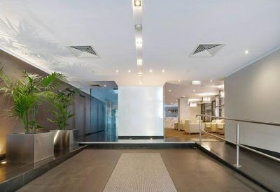 Spacious modern lobby with indoor plants, white feature wall, and warm lighting.