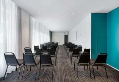 Bright seminar room with rows of black chairs and a teal accent wall.