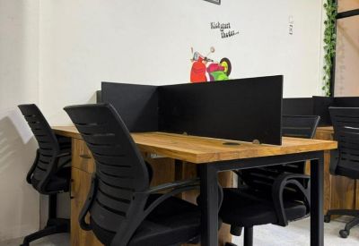 Four-person workstation featuring wooden tabletops, black privacy dividers, and ergonomic mesh chairs.