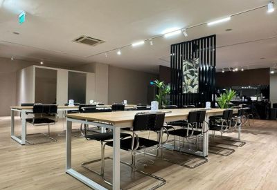 Open-plan workspace at SQ Collective featuring long wooden desks and black cantilever chairs.
