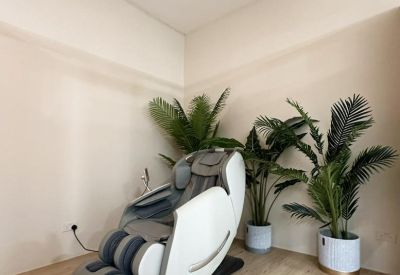 Relaxation area featuring a white high-tech massage chair next to potted palm plants.