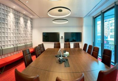 Professional boardroom with a large wood table, red carpet, and floor-to-ceiling windows.