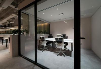 Private glass-enclosed office featuring white desks and ergonomic chairs.