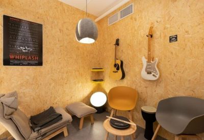 Cozy music-themed breakout room with acoustic wall panels, guitars, and diverse seating.
