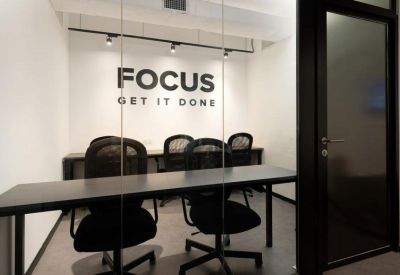 A small meeting room featuring a dark table and a wall with Focus Get It Done signage.