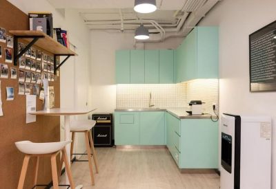 Bright modern kitchen area with light green cabinetry and a tall breakfast bar.
