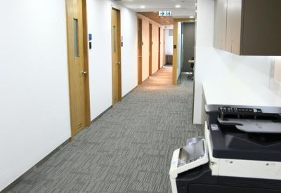 Portrait view of a long office corridor with wooden doors and a carpeted floor.