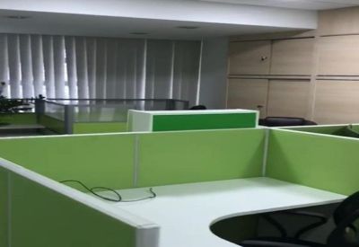 Bright open-plan office with white corner desks and lime green privacy partitions.