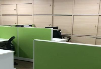 Private office workstation area featuring light wood storage lockers and green dividers.