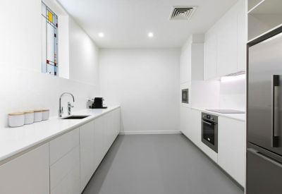Modern communal kitchen area with sleek white cabinetry and integrated appliances.