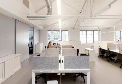 Open-plan workspace with multiple workstations and industrial ceiling details.