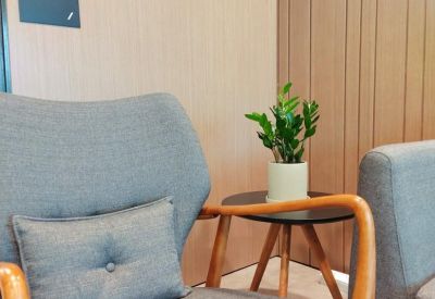 Modern grey armchair and side table with a potted plant against a wood-paneled wall.