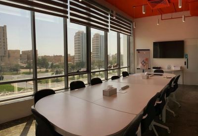 Bright conference room with a large white table, city views, and an orange ceiling.