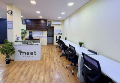 Reception area featuring a branded white desk, wooden flooring, and multiple workstations.