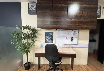 Private office workstation with a wooden desk, black chair, and dark cabinetry.