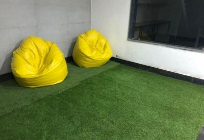 Breakout area with artificial grass flooring and two bright yellow beanbag chairs.