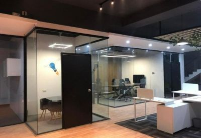 Modern coworking space with glass-partitioned offices and warm wood-style flooring.
