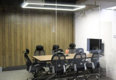 Conference room featuring a long wooden table, ergonomic mesh chairs, and a glass wall.
