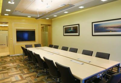 Large boardroom with a long light-wood table, black chairs, and framed artwork on the walls.