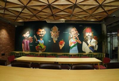 Communal dining area featuring a colorful wall mural of caricatures and a long wooden table.