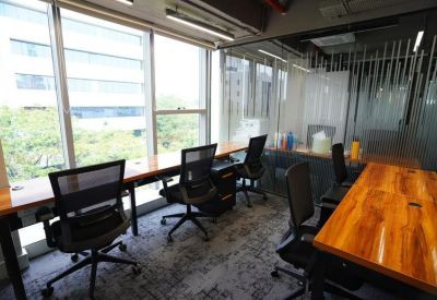 Bright open-plan workspace at Durga Towers with large windows and wooden desks.