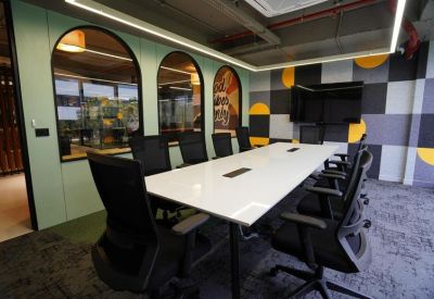 Conference room with a white table, mesh chairs, and a geometric patterned feature wall.
