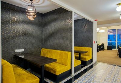 Intimate semi-private meeting booths with vibrant yellow plush seating and patterned wallpaper.