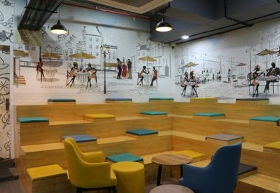 Auditorium-style wooden tiered seating with colorful cushions and street art wall mural.