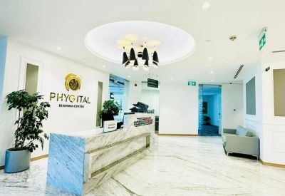 Bright reception area with a marble desk, gold branding, and a modern circular ceiling light.