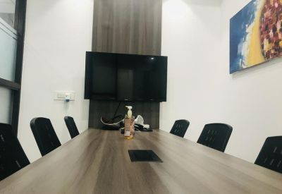 Professional meeting room featuring a long wooden table and wall-mounted television.