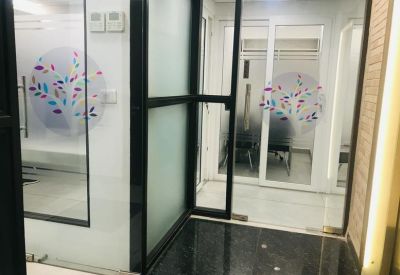 Modern glass-walled entrance with colorful tree decals on the panels.