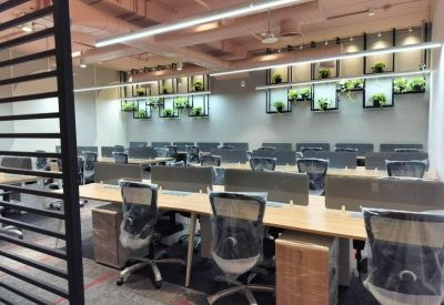 Open-plan workspace with multiple wooden desks and black mesh chairs.
