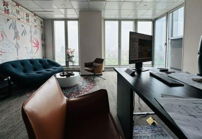 Private office with a dark desk, teal sofa, and botanical wallpaper.