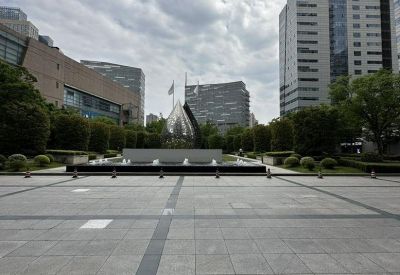 Wide public square with a modern geometric sculpture and city buildings.