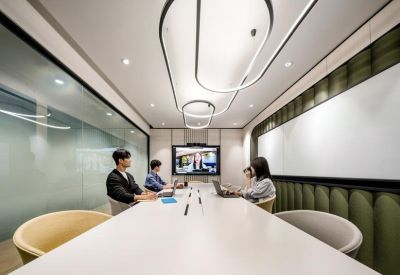 Professional boardroom with a long white table, U-shaped pendant lighting, and video conferencing screen.