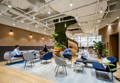 Spacious communal lounge with a spiral staircase, greenery, and diverse seating options.