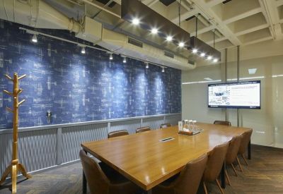 Professional meeting room with a wooden table, leather chairs, and a blue patterned feature wall.