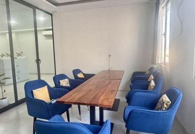 Private meeting room with a wooden table, vibrant blue velvet armchairs, and a ceiling fan.