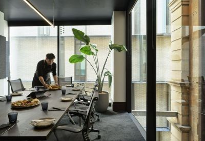 Bright conference room with a long wooden table and large windows overlooking the street.