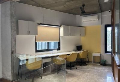 Bright coworking space with white desks and yellow swivel chairs.