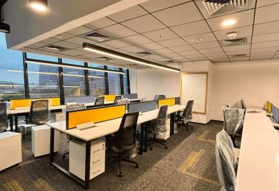 Open-plan office with white workstations, yellow dividers, and industrial-style ceiling.