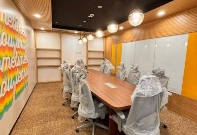 Meeting room with large wooden table, pendant lighting, and colorful wall mural.