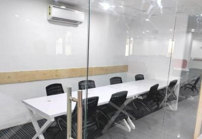 Meeting room with a long white table and black chairs behind a glass partition.