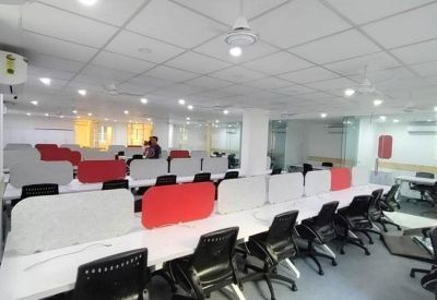 Rows of white desks with red and grey privacy dividers and black ergonomic chairs.