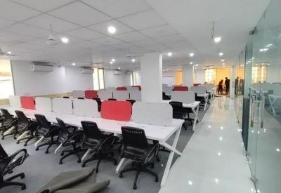 Spacious office layout with white workstations and tiled flooring.