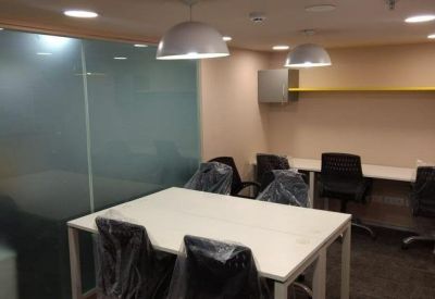 Meeting room with a white table and plastic-wrapped chairs under dome pendant lights.