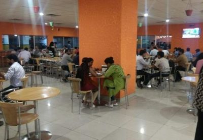 Large communal dining area with orange pillars and numerous small round tables.